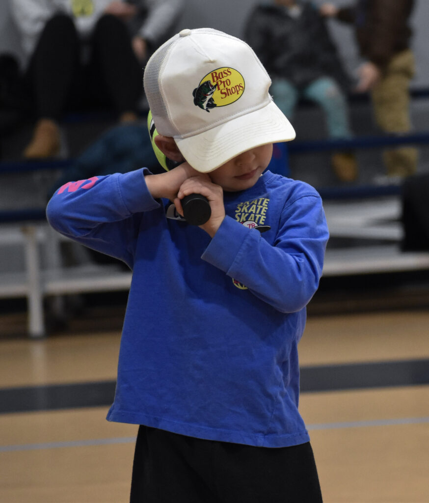 A child holding a baseball bat, about to swing the bat.