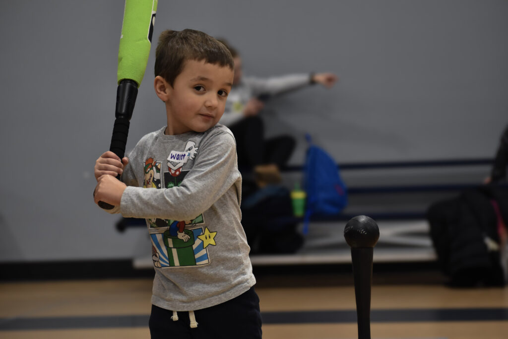 Child holding a bat about to swing and hit a ball off a tee.