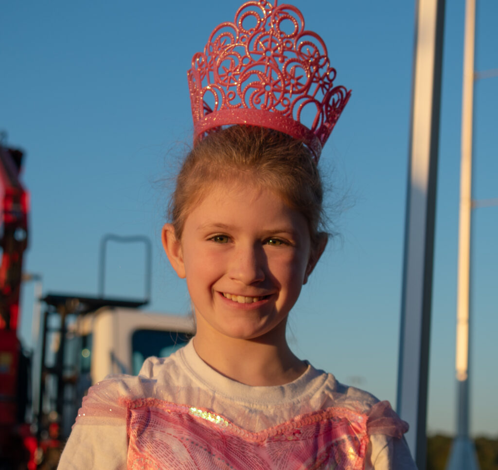 A child in a princess costume smiles while looking at the camera.