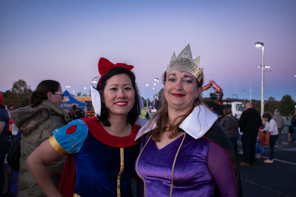 Two women in costumes smiling and posing for a photo.