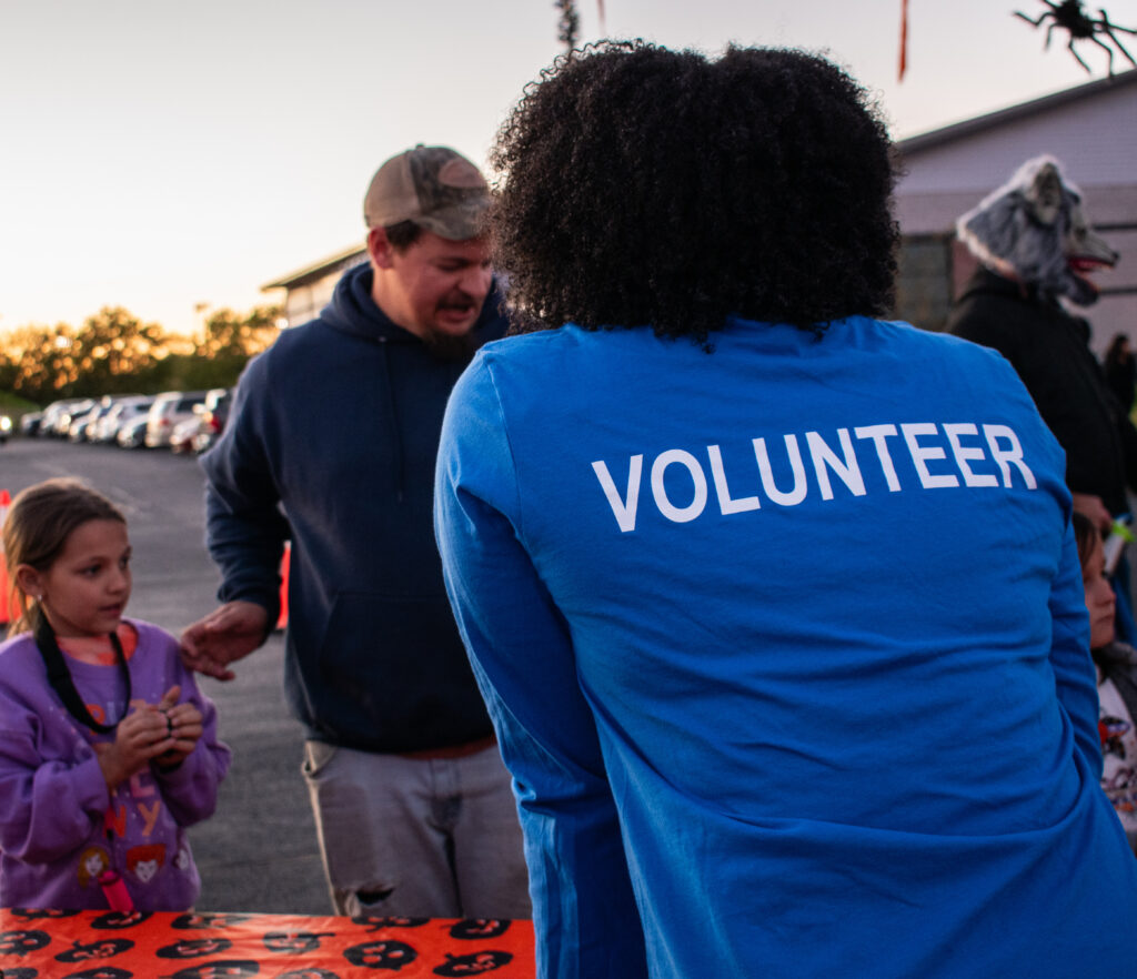 A lady with her back to the camera, wearing a blue shirt that reads, "VOLUNTEER".