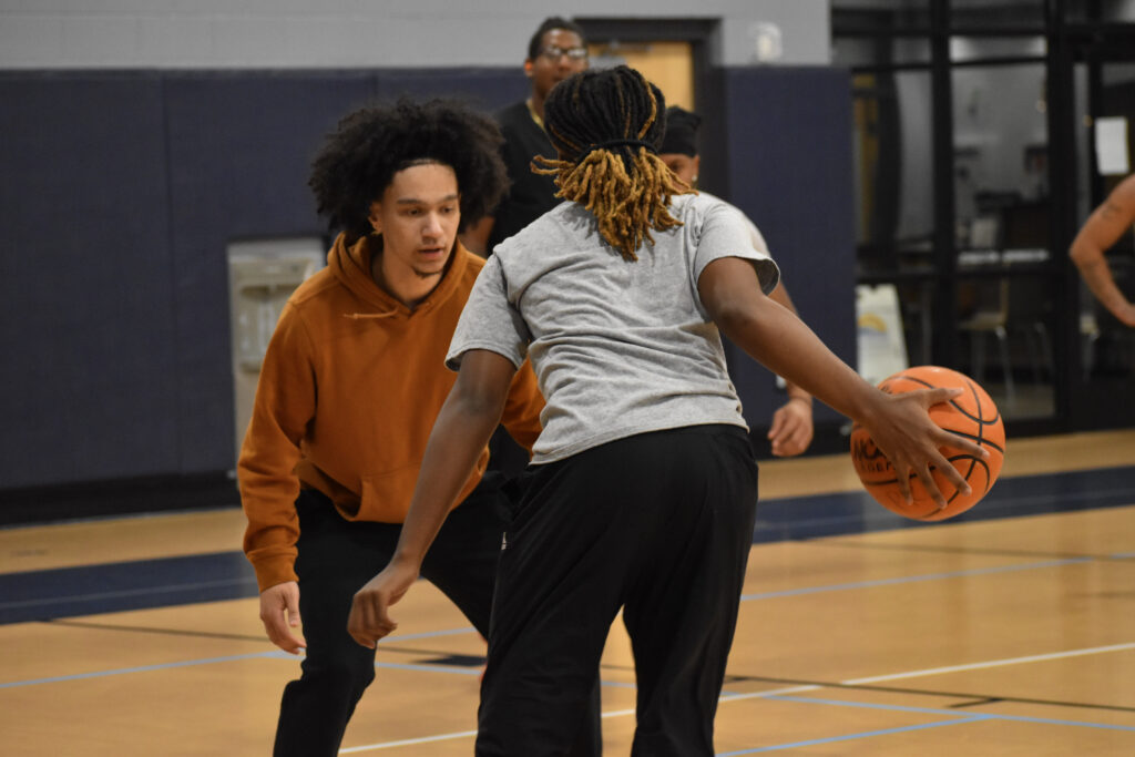 Two basketball players on the court, one on offense and one on defense.