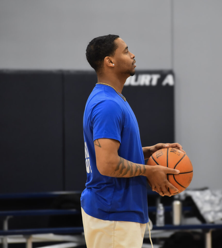 Man standing and looking to the right holding a basketball.