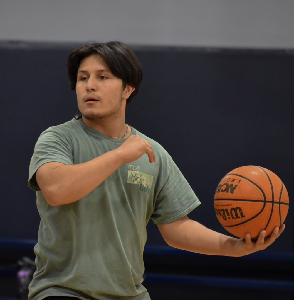 Man facing towards the camera with a basketball in his hand.