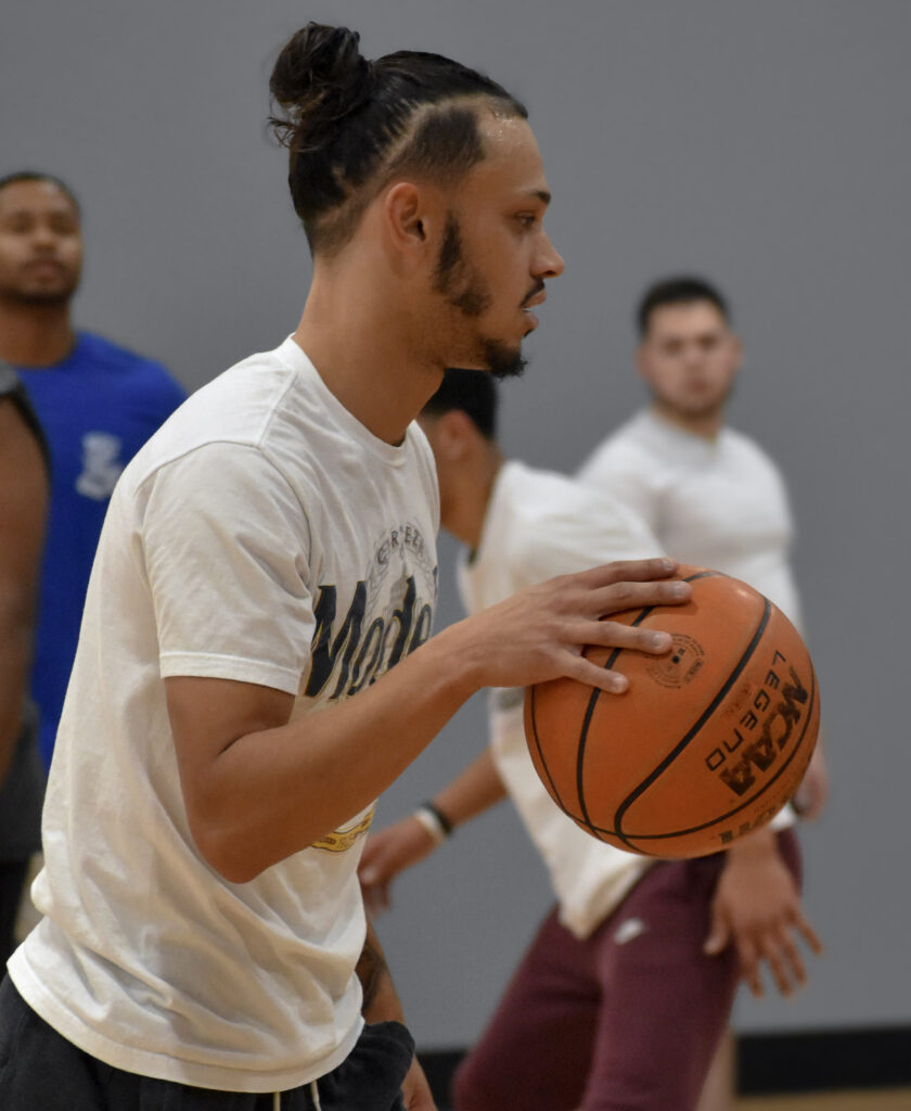 Man dribbling basketball while looking to the right.